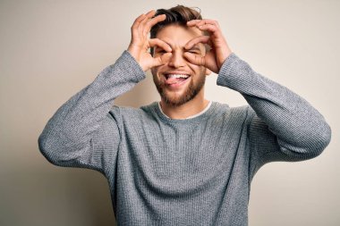 Sakallı ve mavi gözlü genç yakışıklı sarışın adam normal bir jest yapıyor. Dürbün gibi dilini çıkartıyor. Gözleri parmaklarından bakıyor. Çılgın ifade.