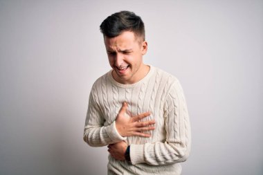 Beyaz tenli arka plan üzerine sıradan bir kazak giyen yakışıklı beyaz bir adam mide bulantısı, acı verici bir hastalık yüzünden el üstünde tutuluyor. Ache kavramı.