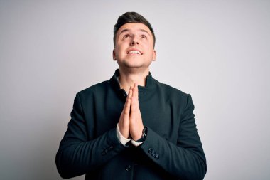 Zarif kışlık ceketler giyen genç yakışıklı iş adamları izole edilmiş arka planda durup umutla el ele yalvarıyor ve dua ediyorlar. Yüzlerinde çok duygusal ve endişeli bir ifade var. Yalvarıyorum..