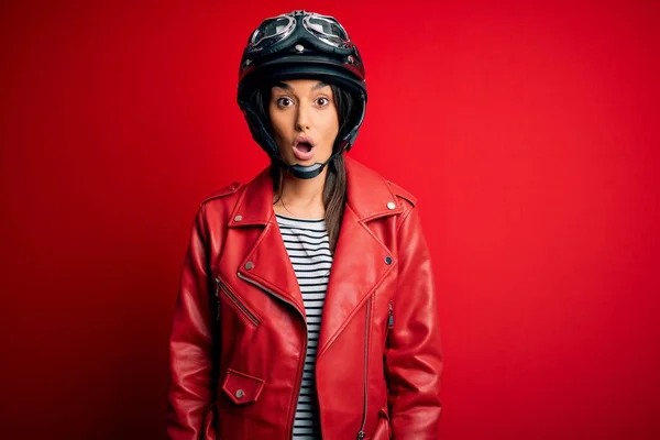若い美しいブルネットのオートバイのヘルメットと赤いジャケットを身に着けているオートバイの女性は恐れていると驚きの表情でショックを受けました 恐怖と興奮した顔 — ストック写真
