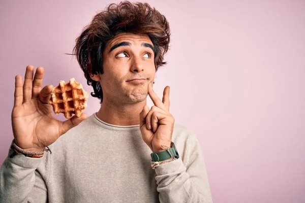 Jovem Homem Bonito Segurando Waffle Doce Sobre Fundo Rosa Isolado — Fotografia de Stock