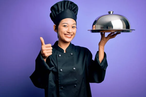 若い美しい中国料理のシェフの女性を着て炊飯器の制服と帽子を保持トレイドーム幸せな大きな笑顔でOkサインを行う 指で親指アップ 優れたサイン — ストック写真