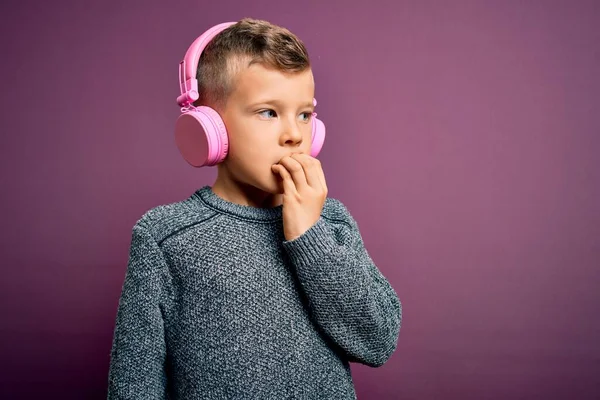 Mladý Malý Běloch Nosí Sluchátka Poslouchá Hudbu Purpurovém Pozadí Vypadá — Stock fotografie