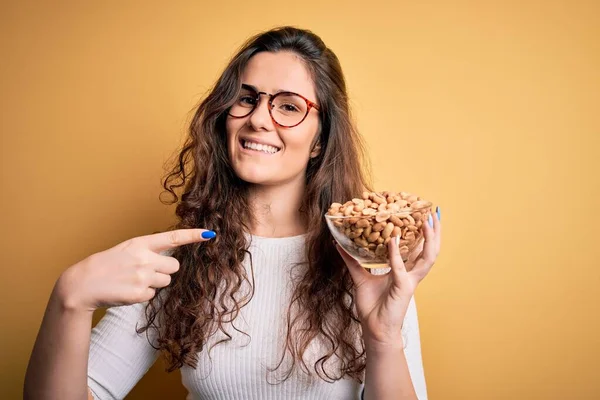 Beautiful Woman Curly Hair Holding Bowl Healthy Peanuts Yellow Background — Stock Photo, Image