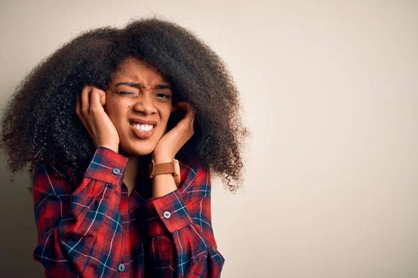 若い美しいアフリカ系アメリカ人女性は 耳を指で覆い 大きな音楽のノイズに悩まされている表情で隔絶された背景にカジュアルなシャツを着ています ろう者の概念 — ストック写真