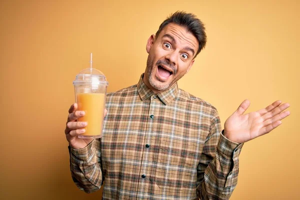 Młody Przystojny Mężczyzna Pije Zdrowy Sok Pomarańczowy Pomocą Słomy Żółtym — Zdjęcie stockowe