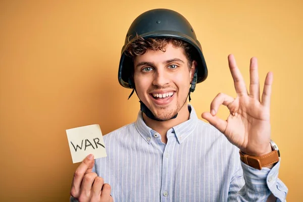 若いですブロンドビジネスマンとともに巻き毛ヘルメット保持紙とともに戦争メッセージを行います指でOkサイン 優れたシンボル — ストック写真