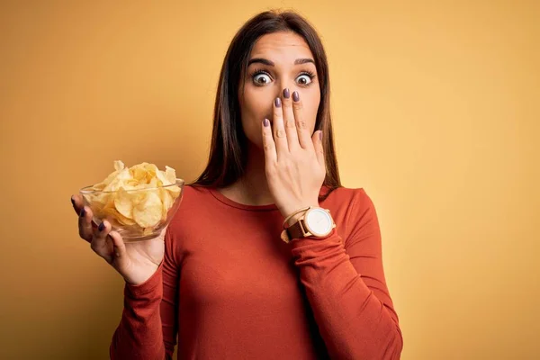 Young Beautiful Brunette Woman Holding Bowl Chips Potatoes Yellow Background — Stock Photo, Image