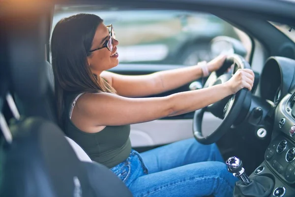 若い美しい女性が幸せと自信を笑顔 笑顔で車を運転している — ストック写真