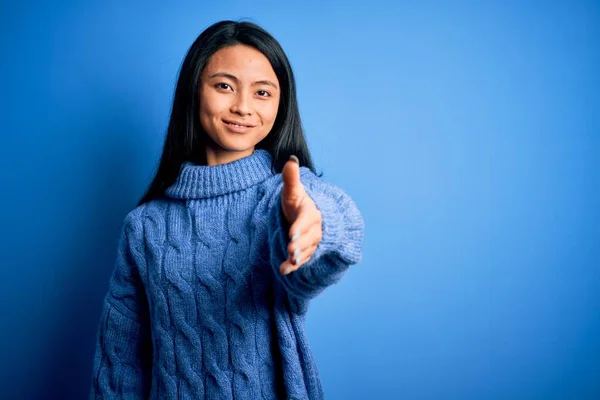 年轻美丽的中国女人穿着休闲装 披着孤立的蓝色背景 微笑友好地握手致意和欢迎 成功的业务 — 图库照片