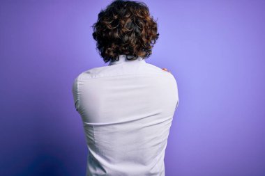 Mor arka planda gömlek giyen sakallı genç yakışıklı iş adamı kendine mutlu ve pozitif bir şekilde sarılıyor. Sevgi ve özgüven.