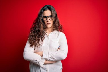 Kıvırcık saçlı, kırmızı arka planda gözlük takan, kuşkucu ve gergin, yüzünde çapraz kollu tasvip etmeyen güzel bir kadın. Negatif kişi.