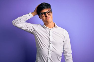 Mor arka plan yüzünden gömlek ve gözlük takan genç yakışıklı iş adamı soru sormayı merak ediyor. Şüpheyle kararsız, kafa kafaya düşünerek. Düşünceli kavram.