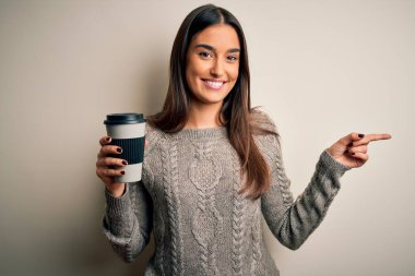 Genç, güzel esmer kadın izole edilmiş beyaz arka planda bir bardak kahve içiyor.