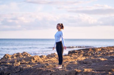 Genç yakışıklı sporcu yoga yapıyor. Koç sahilde dağ pozu öğretiyor.