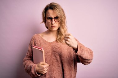 Pembe arka planda gözlük takan güzel, sarışın bir kadın. Sinirli ve sinirli bir şekilde bağırıyor. Öfkeyle bağırıyor.