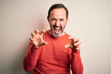 Orta yaşlı, turuncu süveter giyen, izole edilmiş beyaz arka plan üzerinde duran, komik bir şekilde kedi gibi pençe hareketi yapan, agresif ve seksi bir ifade sergileyen, orta yaşlı, beyaz bir adam.