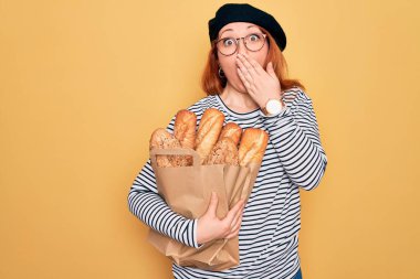 Kızıl saçlı genç bir kadın, elinde kepçe ile sarı arka planda ekmek taşıyan bir çanta tutuyordu. Ağzı kapatıyordu. Yanlışlıkla utancından ağzı açık kalmıştı.