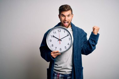 Sakallı ve mavi gözlü genç bir adam pijama giymiş büyük bir saat tutuyor gururla bağırıyor ve zaferi ve başarıyı kutluyor.