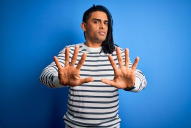 Rastgele çizgili kazak giyen Afro-Amerikan genç yakışıklı afro adam. Avuçlarını kaldırıyor, reddediyor ve iğrenç bir ifadeyle reddediyor. Dur ve yasakla.