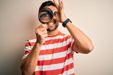 Genç dedektif, izole edilmiş arka planda büyüteçten bakıp gülümseyen ve el pençe divan duran, el pençe divan duran bir adam.