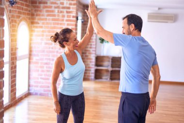 Orta yaşlı güzel sporcu çift mutlu gülümsüyor. Yüzünde gülümsemeyle spor salonunda beşlik çakıyor.