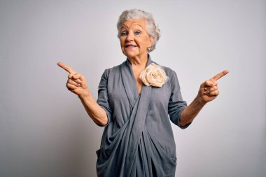 Son sınıf güzeli, gri saçlı, sıradan bir elbise giyen beyaz arka planda duran kendine güvenen, parmaklarıyla farklı yönleri gösteren bir kadın. Reklam için boşluk kopyala