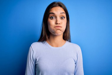 Genç, güzel, esmer, sıradan bir süveter giyen, mavi arka planda dikilmiş komik yüzlü yanakları şişiren bir kadın. Havayla şişmiş ağız, çılgın bir ifade..