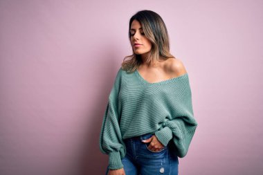 Moda kıyafetleri giyen genç ve güzel bir kadın. Manken, sokak tarzı giyiniyor. Pembe arka planda dikiliyor.