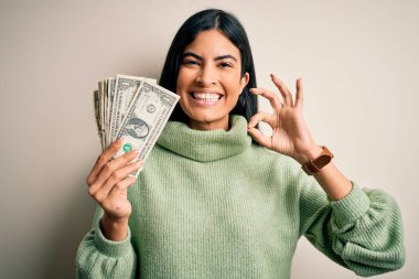 Genç, güzel, İspanyol bir kadın elinde bir deste dolar tutuyor. Tamam işareti yapıyor, mükemmel bir sembol.