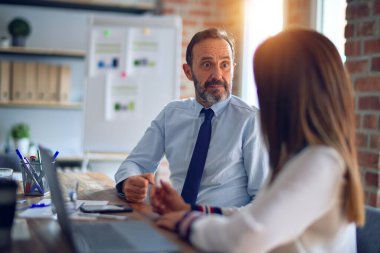 Mutlu ve kendinden emin gülümseyen iki orta yaşlı iş adamı. Ofiste dizüstü bilgisayarla gülümseyerek birlikte çalışıyoruz.