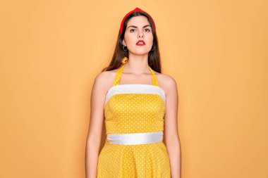 50 'li yılların modasına uygun sarı arka planda elbise giyen genç ve güzel bir kadın. Yüzünde ciddi bir ifadeyle rahatlamış. Basit ve doğal bir şekilde kameraya bakıyorsun..