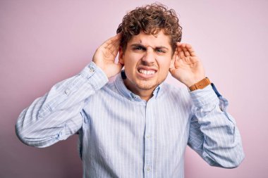 Sarışın, kıvırcık saçlı, beyaz arka planda çizgili tişört giyen, iki elini de kulak hareketi yaparken duymaya çalışan, dedikoduya meraklı genç bir adam. İşitme problemi, sağır