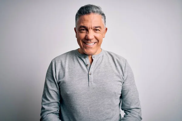 Middle age handsome grey-haired man wearing casual t-shirt over white background with a happy and cool smile on face. Lucky person.