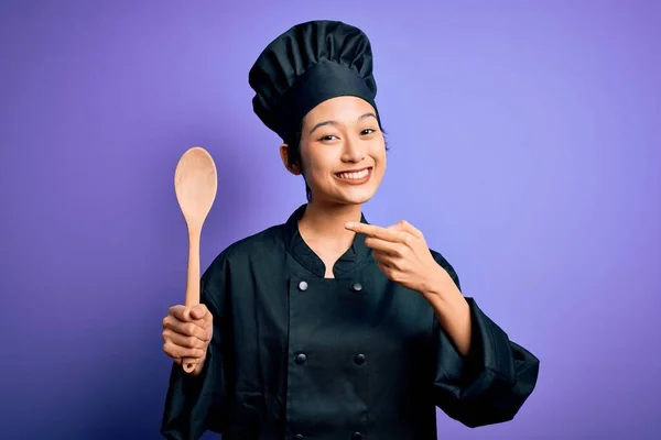 年轻美丽的中国厨师 身穿炊事服 头戴木勺帽 手指手画脚 非常高兴 — 图库照片