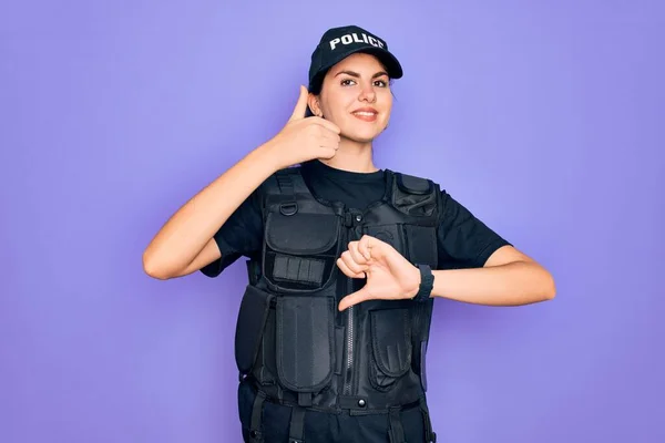 年轻的女警察身穿防弹背心制服 身穿紫色背景的制服 上下翻动大拇指 表示不同意见和同意 疯狂的冲突 — 图库照片