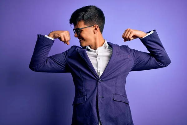Молодой Привлекательный Бизнесмен Пиджаке Очках Изолированном Фиолетовом Фоне Показывает Мышцы — стоковое фото