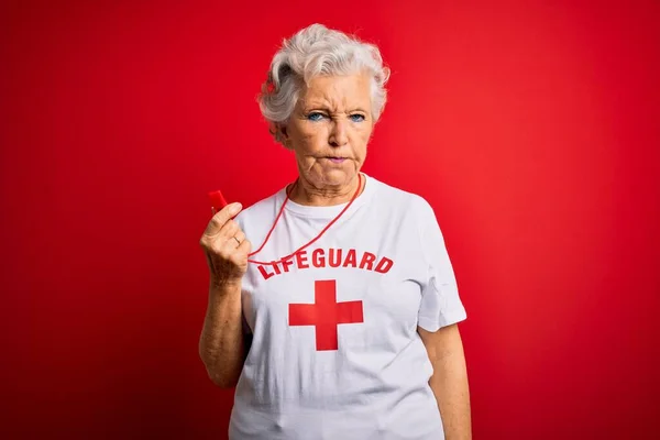 シニア美しい白髪のライフガードの女性は 問題のために動揺を眉をひそめ 懐疑的かつ神経笛を使用して赤いクロスとTシャツを着て 負の人 — ストック写真