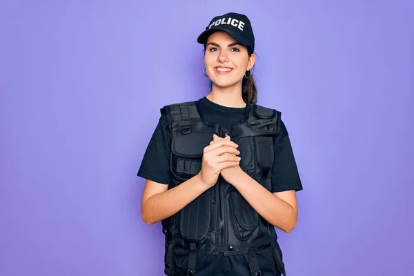 年轻的女警察身穿防弹背心 身穿紫色背景制服 双手合十 双手交叉 微笑着 轻松愉快 成功与乐观 — 图库照片