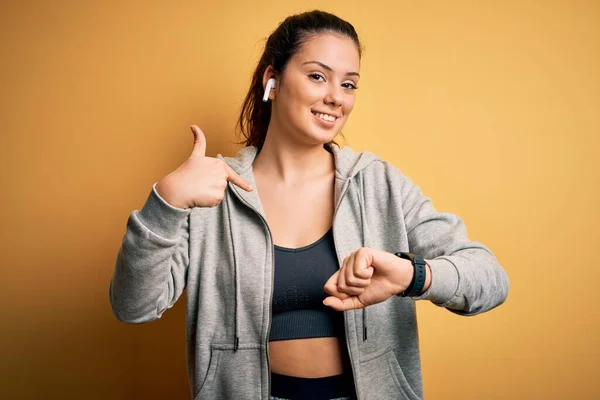 若い美しいブルネットのスポーツ女性は自分自身に指を指す驚きの顔でスポーツをやってイヤフォンを使用して音楽を聴く — ストック写真