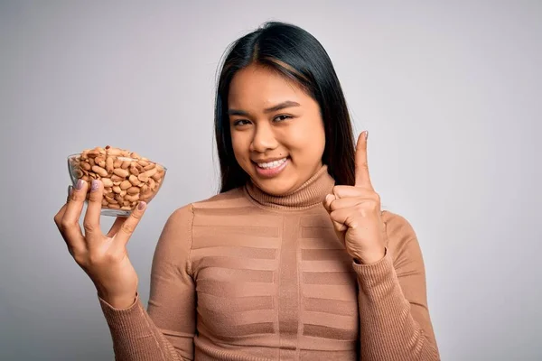 Genç Asyalı Kız Elinde Sağlıklı Fıstıklarla Beslenme Alışkanlığı Olarak Beyaz — Stok fotoğraf