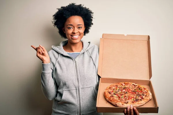 若いですアフリカ系アメリカ人アフロ女性とともに巻き毛保持デリバリーボックスとともにイタリアのピザ非常に幸せなポインティングとともに手と指へ側 — ストック写真