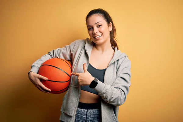 Jovem Bela Morena Esportista Segurando Bola Basquete Sobre Fundo Amarelo — Fotografia de Stock