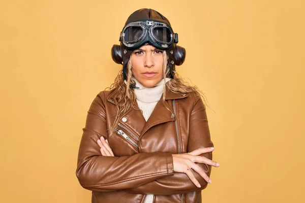 若い美しいブロンドのアビエイターの女性は ヴィンテージパイロットヘルメットホワイトの眼鏡を着用し ジャケット懐疑的で緊張し 両腕を組んで顔に不承認式 負の人 — ストック写真