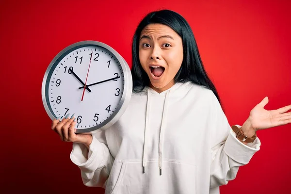 Jovem Mulher Chinesa Bonita Segurando Grande Relógio Sobre Fundo Vermelho — Fotografia de Stock
