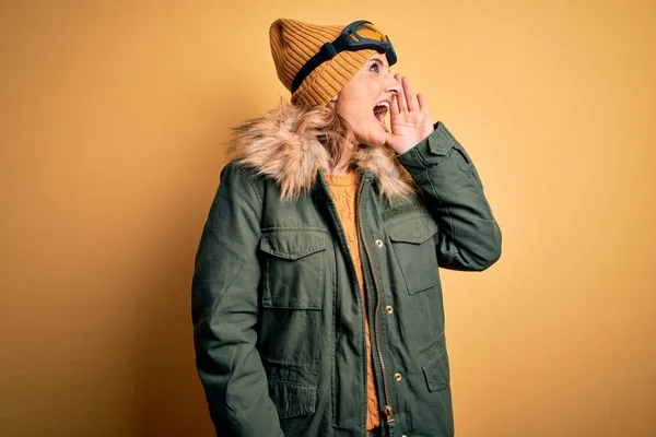 中年漂亮的金发滑雪者女人穿着雪地运动鞋和滑雪护目镜 一边大喊一边大叫 传播概念 — 图库照片