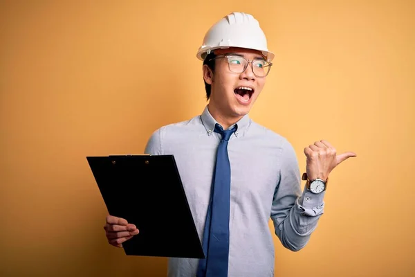 Joven Ingeniero Chino Guapo Con Casco Seguridad Sosteniendo Portapapeles Apuntando — Foto de Stock