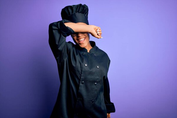 Young african american chef girl wearing cooker uniform and hat over purple background covering eyes with arm smiling cheerful and funny. Blind concept.