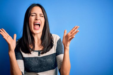 Mavi gözlü, sıradan çizgili tişörtler giyen genç esmer kadın, arka planda dikilmiş başarıyı kutluyor, kolları havada ve gözleri kapalı, heyecanlı bir şekilde çığlık atıyor. Kazanan konsept