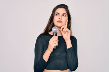 Genç, güzel şarkıcı kız, izole edilmiş arka planda müzik mikrofonuyla şarkı söylüyor.
